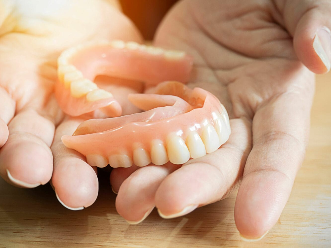Close up of female hands holding flexible nylon denture. Dental prosthesis in the hands. Dentistry conceptual photo. Prosthetic dentistry. False teeth
