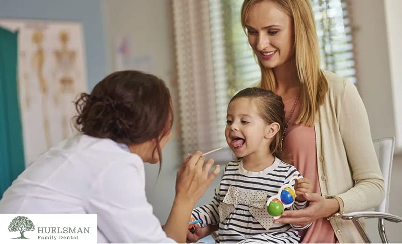 Pediatric dentist checking a child’s teeth during a dental exam